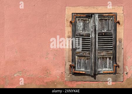 Weathered, wooden, louvered window shutters on a wall, create an interesting European still life scene. Stock Photo