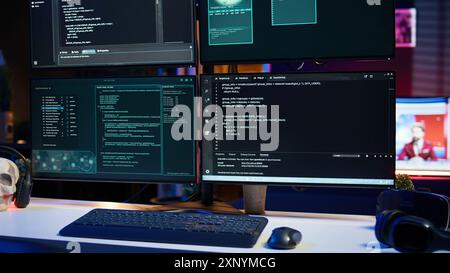 Close up of code running on computer displays in empty apartment used by hacker stealing secrets. Illegal scripts on PC screens used by spy infiltrating governments, handheld camera shot Stock Photo