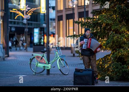 First day of the Christmas lockdown in the Corona crisis, empty shopping alleyway Schildergasse, lonely alleyway musician in front of a Christmas Stock Photo