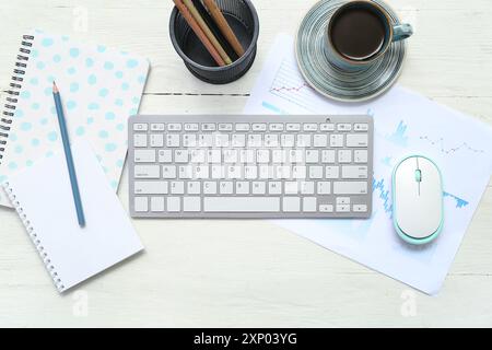 Composition with keyboard, coffee and blank notepad on light wooden background Stock Photo