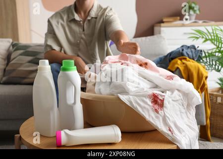 Young man taking dirty clothes from laundry basket at home Stock Photo