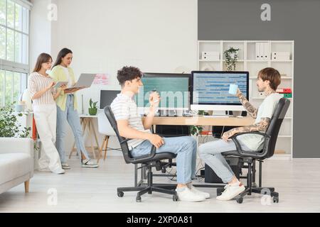 Male programmers with cups of coffee working at table in office Stock Photo