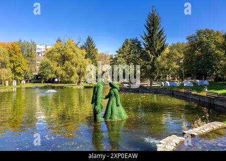 Razlog, Bulgaria, October 20, 2020: Lake, man and woman green leafs figurines panoramic view with autumn trees and fountains Stock Photo