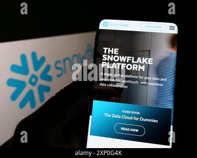 Stuttgart, Germany, 03-05-2022: Person holding cellphone with webpage of US software company Snowflake Inc. on screen in front of business logo. Stock Photo
