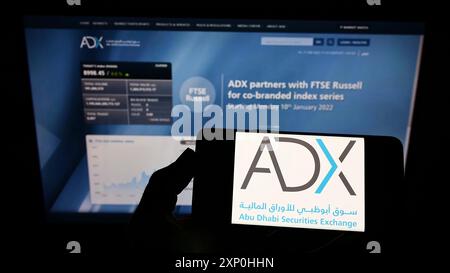 Stuttgart, Germany, 02-11-2022: Person holding smartphone with logo of company Abu Dhabi Securities Exchange (ADX) on screen in front of website. Stock Photo