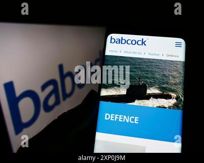 Stuttgart, Germany, 01-30-2022: Person holding cellphone with webpage of British company Babcock International Group plc on screen with logo. Focus Stock Photo