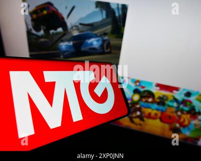 Stuttgart, Germany, 01-29-2022: Mobile phone with logo of Swedish company Modern Times Group AB (MTG) on screen in front of business website. Focus Stock Photo