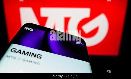 Stuttgart, Germany, 01-29-2022: Smartphone with website of Swedish company Modern Times Group AB (MTG) on screen in front of business logo. Focus on Stock Photo