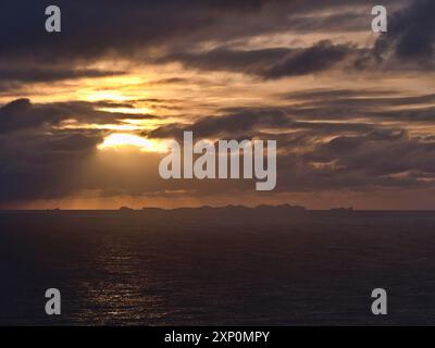 Stunning sunset above Atlantic ocean with dramatic sky of sun breaking through clouds with the silhouettes of Vestmannaeyjar islands, Iceland Stock Photo