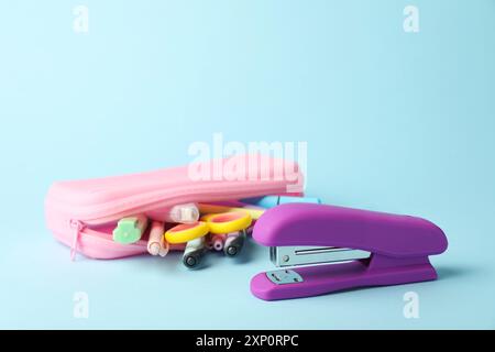 Violet stapler and other stationery on light blue background, closeup Stock Photo