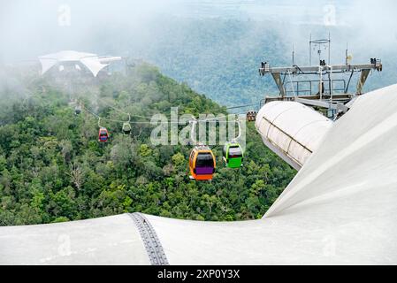 Cable gondolas travel up and down,through clouds,along cables connecting the two stations,over the forested mountain peaks of Mat Cincang.Mid station Stock Photo