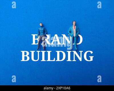 Miniature people with text BRAND BUILDING on a blue background. Stock Photo