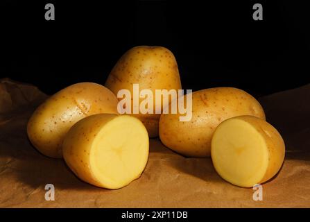 WHOLE AND SLICED POTATOES RUSTIC STYLE ON DARK BACKGROUND Stock Photo
