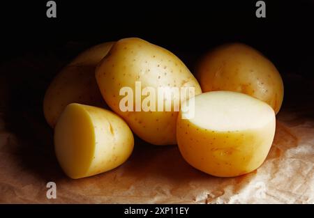 RAW POTATOES THROWN ON BROWN PAPER IN THE DARK BACKGROUND Stock Photo