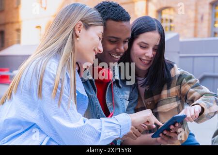 Three students having fun with mobile phones creating content on social media. Stock Photo
