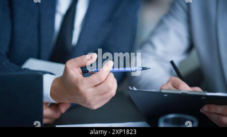 A team of two busy professionals working together using a report and looking at papers. An executive explaining the company's online project strategy Stock Photo