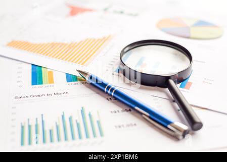 Magnifying glass and pen on financial charts graphs. Annual document report Stock Photo