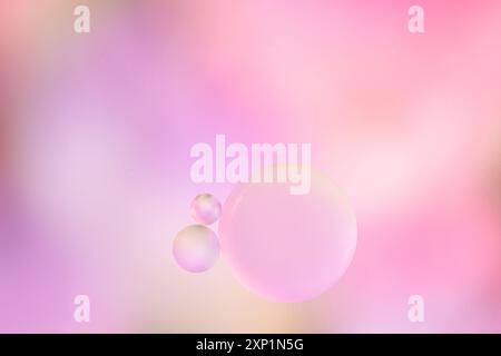 Macro drops of oil on the surface of the water. Delicate cosmetic bubbles background for advertising cosmetic products in soft pink beige tones. Stock Photo