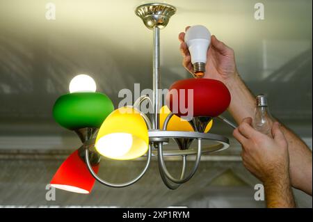 Replacing an incandescent light bulb with an LED one in a lamp Stock Photo