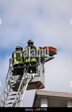 Vicenza, VI, Italy - May 23, 2024: Italian firefighters on top of the basket truck with the stretcher during the rescue of the injured man on the roof Stock Photo