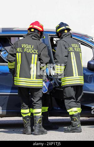 Vicenza, VI, Italy - May 23, 2024: Two firefighters using the Jaws of Life to pry open the door of a wrecked car Stock Photo