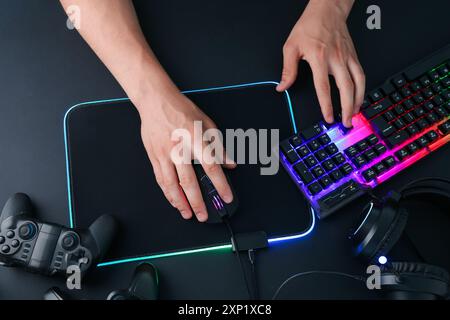 Gamer using modern wired computer mouse at black table, top view Stock Photo