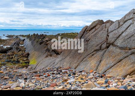 The distinctive lichen covered rocks that form part of the ancient sea defences on St Monans shore line and harbour. Stock Photo