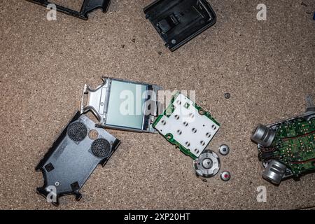 High-angle view of a disassembled sound recorder with various electronic parts scattered on a textured surface. Ideal image for themes of repair, recycling, technology, and electronics. Stock Photo
