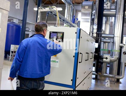 Engineer adjusting controls on a cogeneration unit in a modern industrial facility. Focus on energy efficiency and environmental sustainability. Stock Photo