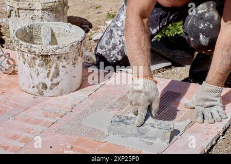 House painter applies cement based adhesive mortar to reinforcement mesh of cladding panel with false brickwork. Stock Photo