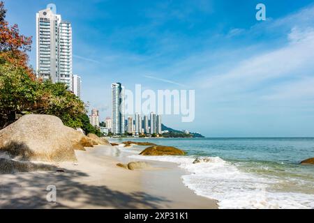 A view along Tanjing Tokong beach in Penang, Malaysia with tall, modern, skyscrapers, part of a city skyscape in the background. Stock Photo