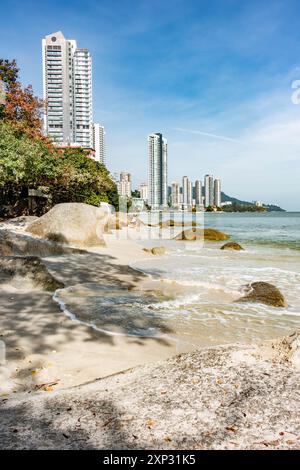 A view along Tanjing Tokong beach in Penang, Malaysia with tall, modern, skyscrapers, part of a city skyscape in the background. Stock Photo