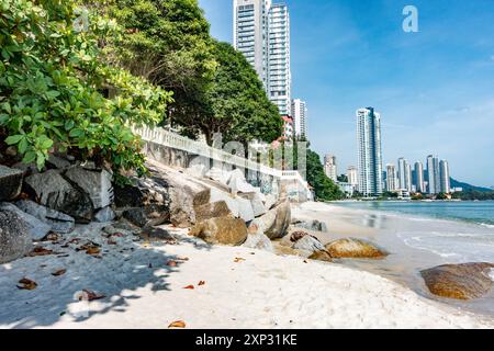 A view along Tanjing Tokong beach in Penang, Malaysia with tall, modern, skyscrapers, part of a city skyscape in the background. Stock Photo