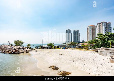 A view along Tanjing Tokong beach in Penang, Malaysia with tall, modern, skyscrapers, part of a city skyscape in the background. Stock Photo