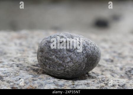 A small round rock lying on top of a large rock. Stock Photo
