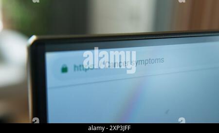 A close-up shot of a computer monitor displaying a web browser with the search query "cancer symptoms" in the address bar. The use of online resources Stock Photo