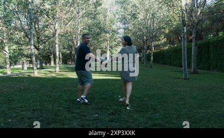 A man and woman are walking in a park, holding hands. Scene is romantic and peaceful Stock Photo