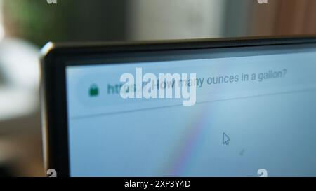 Close-up shot of a computer monitor displaying a web browser with search query "how many ounces in a gallon?" in address bar. Stock Photo