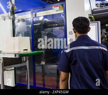 Industrial technician operates injection molding press machine Industrial plastic manufacturing. Stock Photo