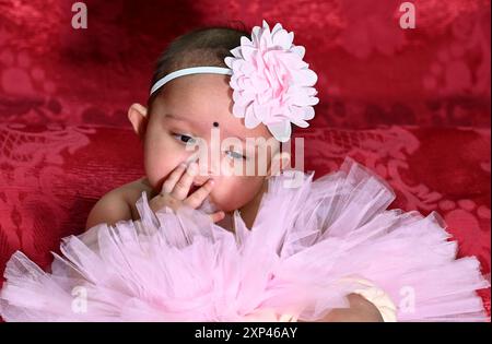 Cute little baby girl wear colorful dress with hair band  she playing  and happy for her activities in the rice ceremony occasion. Stock Photo