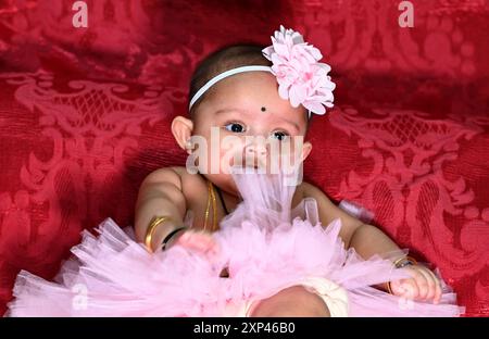 Cute little baby girl wear colorful dress with hair band  she playing  and happy for her activities in the rice ceremony occasion. Stock Photo