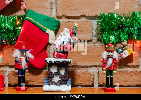 Festive decorations with Santa, nutcrackers, and stockings against a brick wall Stock Photo