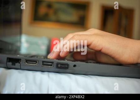 fingers of a child pressing keys of laptop to play games Stock Photo