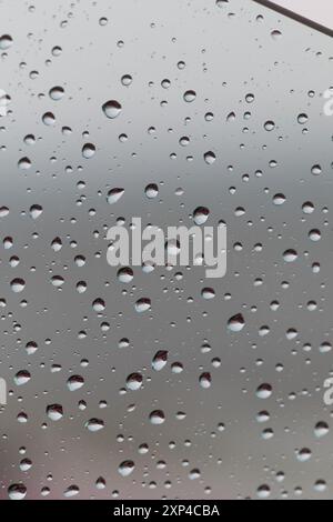 Raindrops on window glass with blurred background creating a serene atmosphere Stock Photo