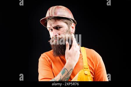 Builder man. Male builder, civil engineer in protective hard hat and overalls. Serious industrial worker, foreman or repairman in safety hardhat. Port Stock Photo