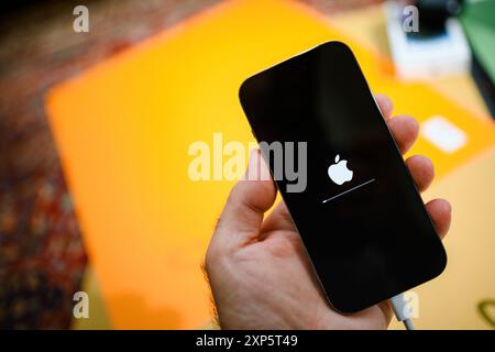 Paris, France - Oct 28, 2022: A male hand holding an Apple iPhone with the Apple logo and a progress bar displayed on the screen, indicating a software update, set against a colorful blurred background Stock Photo