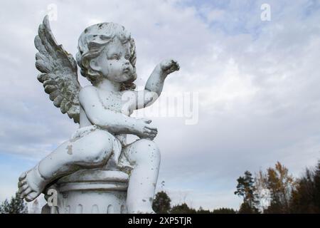 Sad angel sculpture with open long wings across the frame Sad angel sculpture with open long wings across the frame
