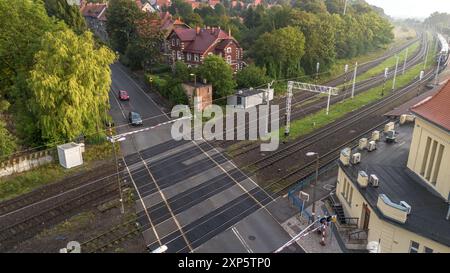 Train Tracks Crossing Near Residential Area With Cars and Pedestrians in Early Morning Light Stock Photo