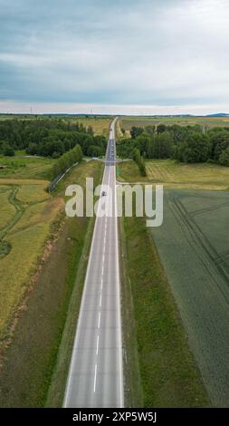 Aerial View of Long Straight Country Road Surrounded by Vibrant Green Fields Stock Photo