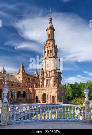 A beautiful blue and yellow tiled railing on a bridge sits in front of the south tower of the Plaza de Espana in Seville Spain. Stock Photo
